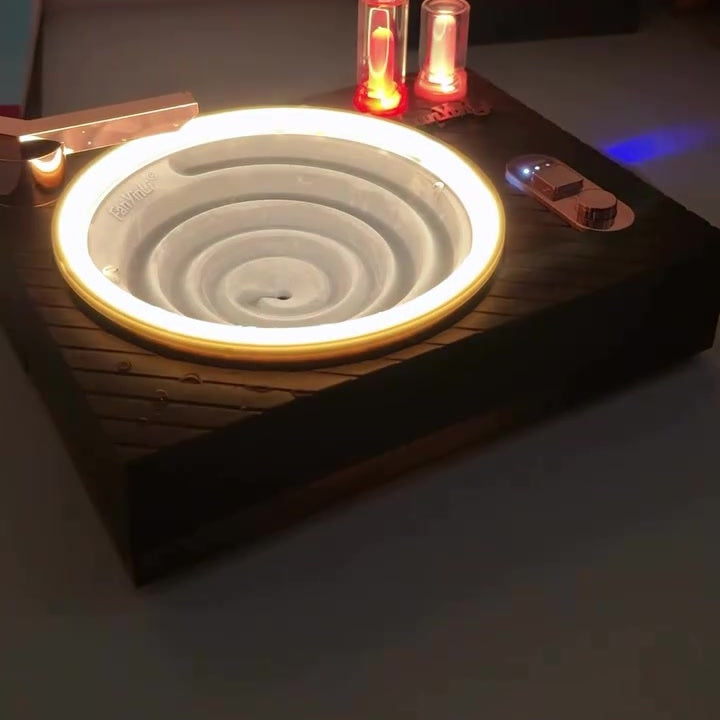 Record player style water drop player glowing in dim room